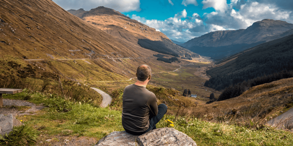 a man sitting on the side of a mountain